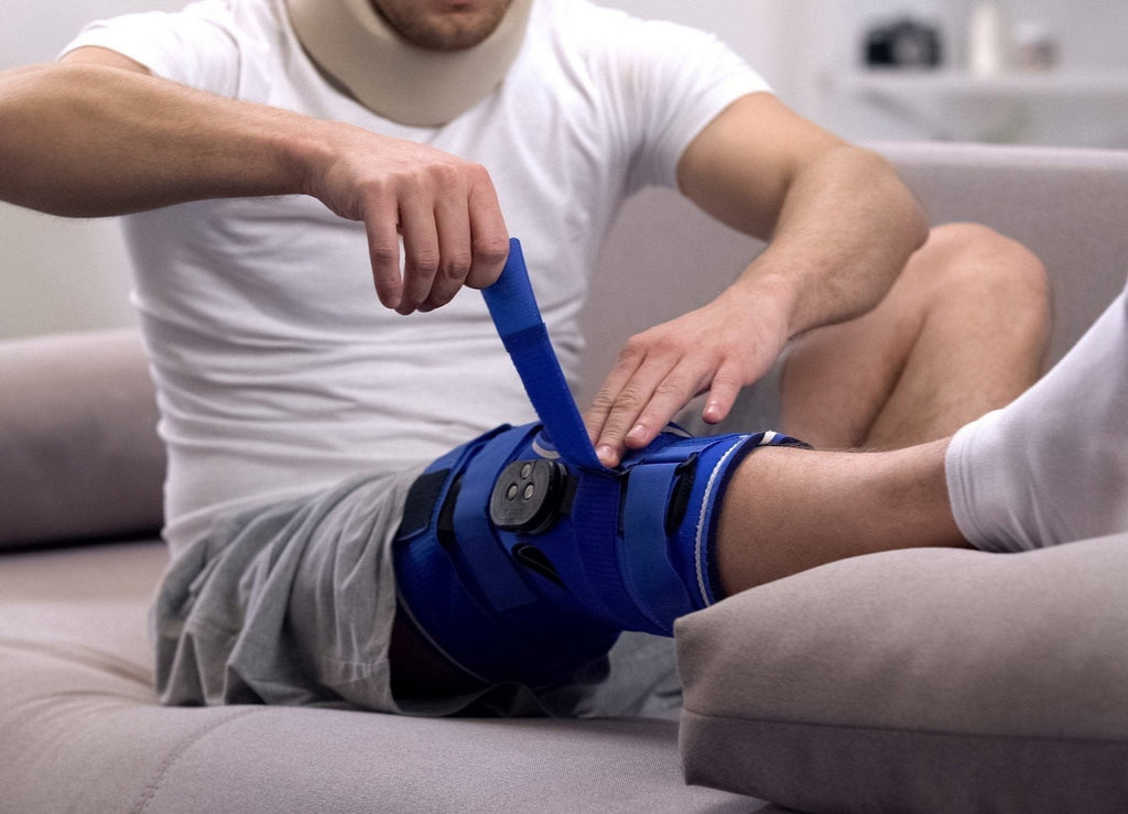 a man is putting on a knee brace using hook and loop tape.